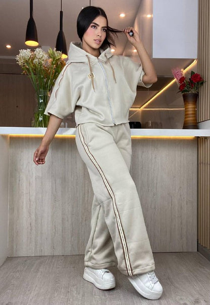 Mujer con conjunto beige de pantalón y chaqueta deportiva con rayas, en cocina moderna