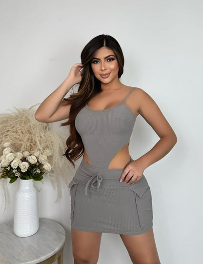 Mujer con conjunto de body y falda gris, vestido ajustado, fondo blanco minimalista.